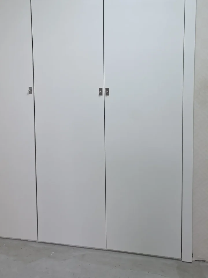 흰색 도어 세 짝 붙박이장 도어 하단과 손잡이 근접 모습